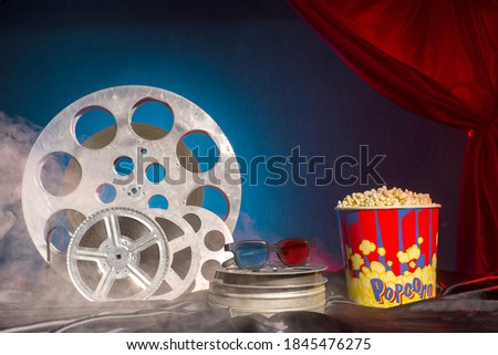 Old film reels, popcorn and 3d glasses on the table. Focus on glasses. Multicolored background. Evolution Film Media
