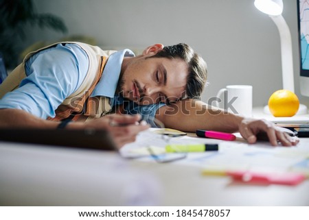 Tired exhausted young entrepreneur fell asleep at his desk after working on project all day long Royalty-Free Stock Photo #1845478057