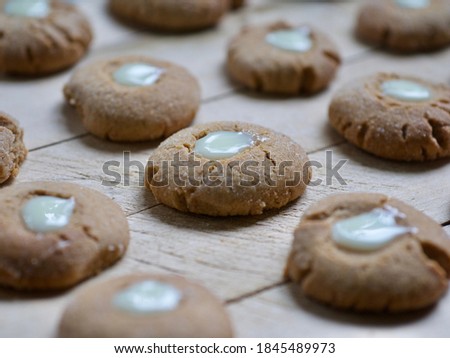 many small round fresh ginger, honey and cinnamon cookies with a creamy eye assorted on a chopping board