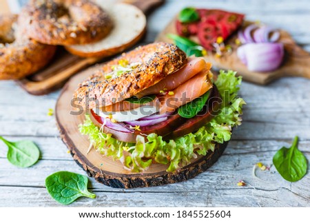 Takeaway food. Bagel burger with smoked salmon and fresh vegetables. Royalty-Free Stock Photo #1845525604