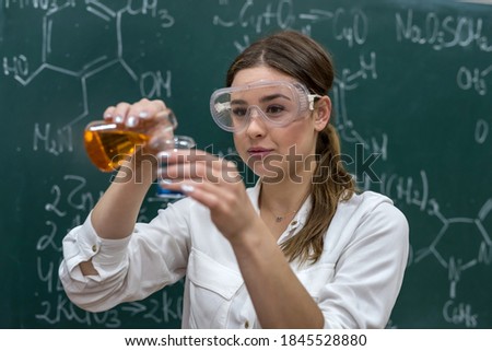 female teacher mixing multi colored chemical liquids together during a chemistry lesson. scientific