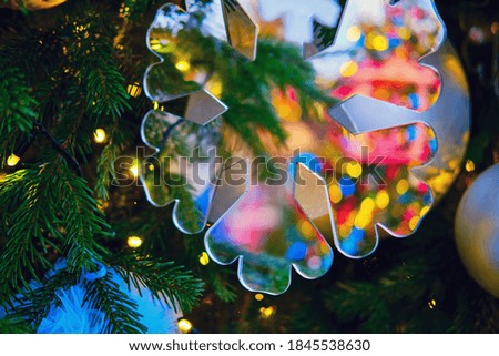 Mirror snowflake hanging as a decoration on a green Christmas tree, close-up