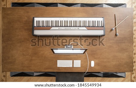 Top view of musical keys and computer on a large wooden table. Musician workplace, musical minimalism.