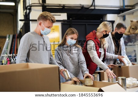 Group of volunteers in community charity donation center, food bank and coronavirus concept. Royalty-Free Stock Photo #1845553696
