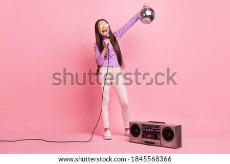 Full size photo of little kid girl sing song mic hold disco ball with retro boom box isolated on pastel color background