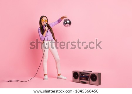 Full length photo of little kid girl sing song mic hold disco ball with boom box isolated over pastel color background