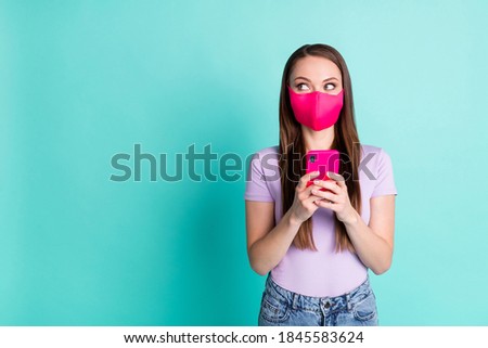 Photo portrait of young girl wearing pink fabric mask using smartphone isolated on bright teal color background with blank space
