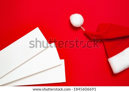 Three white wood planks and Santa Claus hat on a red background. Banner with Christmas or new year mood with a free place for text for a hardware store or art shop or business card.