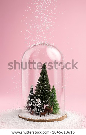 Christmas layout made with pine tree, dear and snow under the glass dome on pink background. Minimal New winter or Year season wallpaper. Holidays self-isolation and coronavirus pandemic concept.