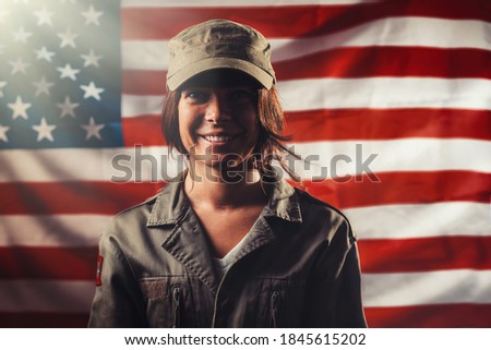 Veterans Day, Memorial Day, Independence Day. Portrait of a smiling female soldier posing against the background of the American flag. Light