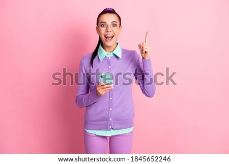 Photo of cute woman hold telephone direct finger up open mouth wear specs violet cardigan isolated pink color background