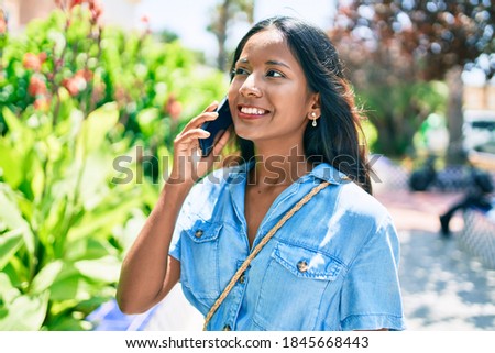 Young beautiful indian woman smiling happy having conversation talking on the smartphone at the park