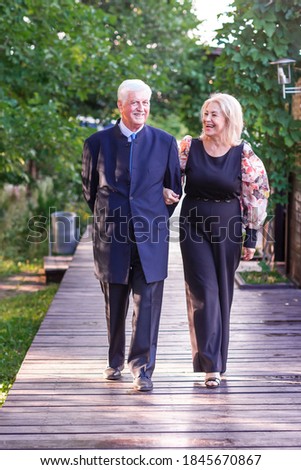 Beautiful elegant senior couple walking in the park having nice time together