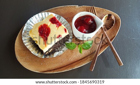 Cheesecake with strawberry sauce and icing sugar on a brown wooden plate ready to serve.