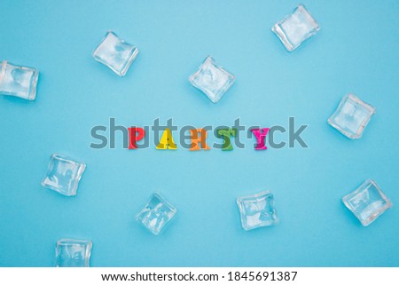 Word PARTY on a blue background of wooden multicolored letters, ice cubes around the word.