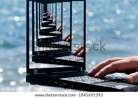 The Droste effect concept: Laptop with hand in front of blue sea with picture recursively appearing within itself on laptop's monitor Royalty-Free Stock Photo #1845691393