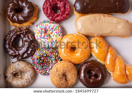 A top down view of a dozen donuts in a cardboard box.