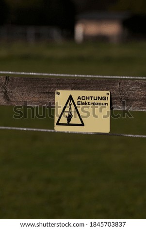 Electricity warning sign on a wood fence, electric fence