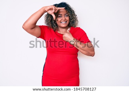 Young african american plus size woman wearing casual clothes smiling making frame with hands and fingers with happy face. creativity and photography concept. 