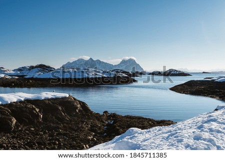 Beautiful winter landscape with sea and steep mountains near Svolvaer on the Lofoten islands in Norway with snow on clear day with blue sky