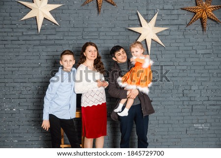 A big, cheerful, friendly family on the set in the studio, against the background of a brick wall with stars.