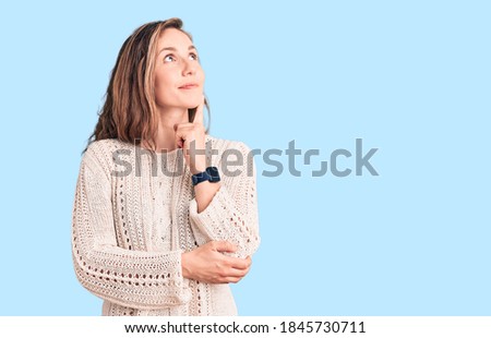 Young beautiful blonde woman wearing casual sweater with hand on chin thinking about question, pensive expression. smiling and thoughtful face. doubt concept. 