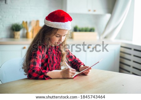 Cheerful curly girl in santa claus hat at home smiling