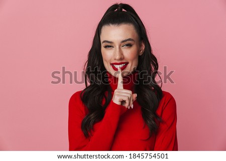 Portrait of beautiful young woman standing over isolated pink background, asking to be quiet with finger on lips