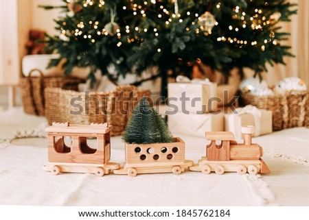 Children's wooden toy decoration wooden train close-up on the background of the Christmas tree and gifts