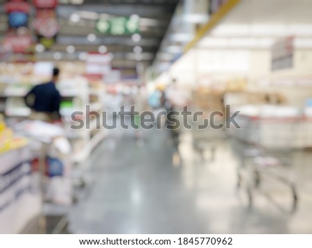 Blurred image of people shopping in supermarket. Cashier with long line of people waiting at checkout counter in fitness store at outlet shopping mall in Thailand. 