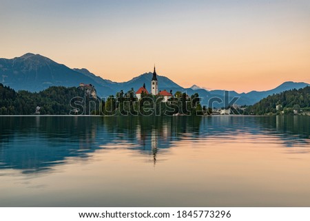 A picture of Lake Bled, centered on the Lake Bled Island, at sunset, taken from the margin.