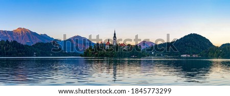 A panorama picture of Lake Bled, centered on the Lake Bled Island, at sunset, taken from the margin.