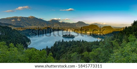 A panorama picture of Lake Bled and the surrounding landscape, with the Lake Bled Island in the middle, as seen from a vantage point.