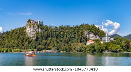 A picture of Bled Castle and the St. Martina Parish Church overlooking one of Lake Bled's gondolas, named "pletna".