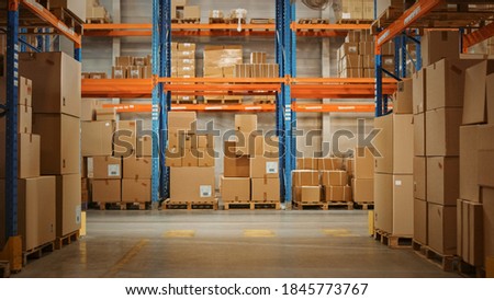 Gigantic Sunny Retail Warehouse full of Shelves with Goods in Cardboard Boxes. Logistics and Distribution Storehouse Center for further Product Delivery Packages. Front Camera View Royalty-Free Stock Photo #1845773767
