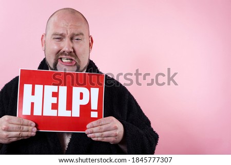 Studio photo of a crying man holding a red sign with the work HELP.