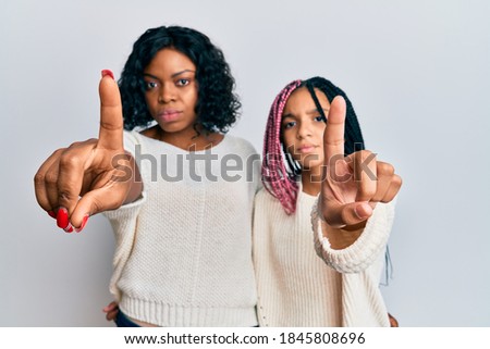 Beautiful african american mother and daughter wearing casual clothes and hugging pointing with finger up and angry expression, showing no gesture 