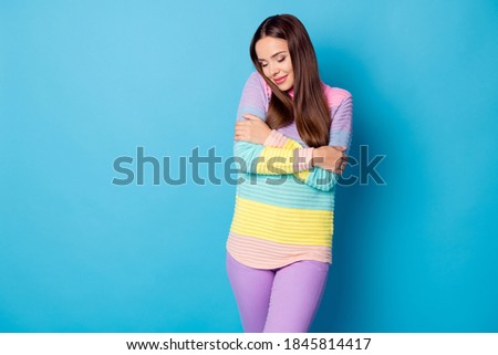 Photo of cute pretty girl hug herself warm sweater wear trousers isolated over blue color background