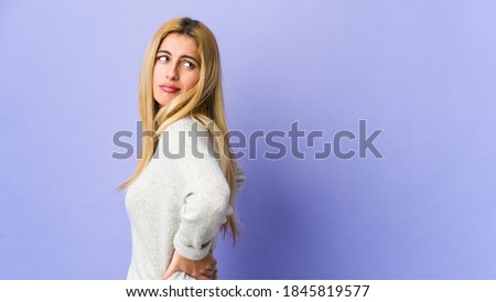 Young blonde woman isolated on purple background suffering a back pain.