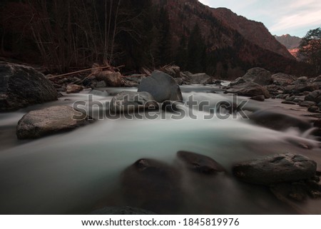 Long exposition shot of a river with silk effect on the water, while the rocks and background are sharp in focus. No people are visible.