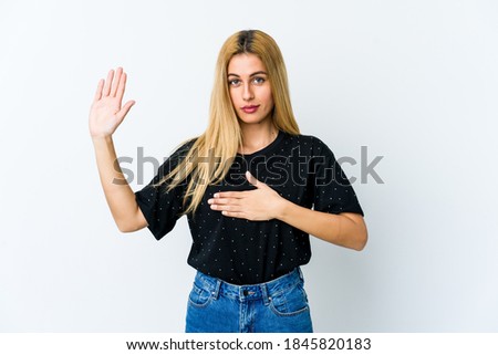 Young blonde woman isolated on white background taking an oath, putting hand on chest.