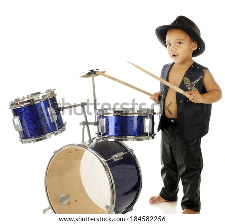 An adorable, barefoot preschooler dressed as a rock star, beating on a drum set.  On a white background.  Motion blur on the drum sticks.