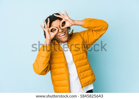 Young mixed race man showing okay sign over eyes