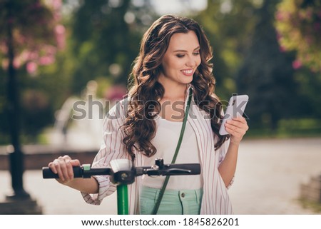 Photo of pretty cheerful sporty girl drive segway chat telephone wear striped shirt enjoy summer fresh air outside