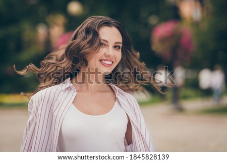 Photo portrait photo of pretty female student throwing hair on windy weather walking in green city park in spring