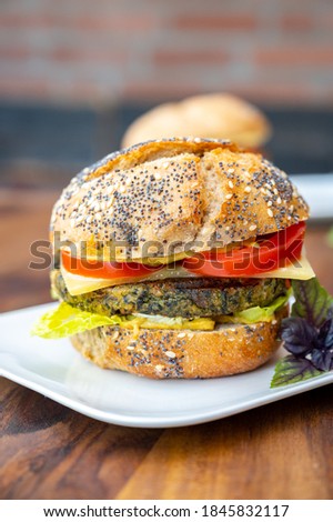 Eating of fresh and healthy vegetarian hamburgers with grilled spinach or pumpkin burgers, organic buns and vegetables close up