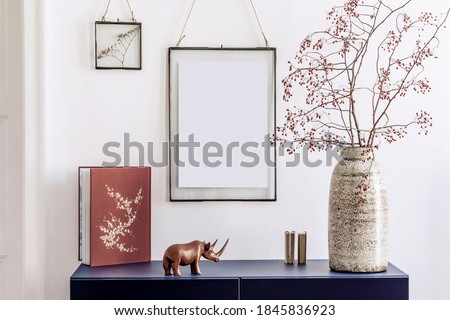 Stylish living room interior with mock up poster frames, navy blue commode, book, decoration and elegant personal accessories in modern home decor.  White wall. Template.