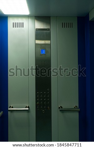 Elevator wall with floor buttons panel. Screen with current floor number and handrails for users. The elevator car from the inside while driving.
