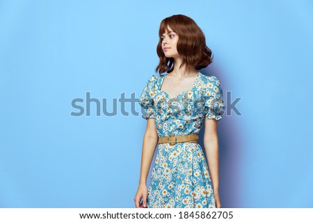 Woman in fashionable dress looking away blue background short hair 