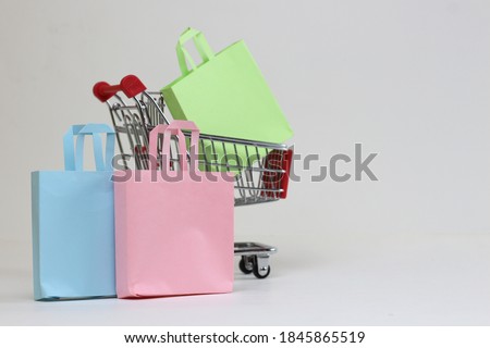 colored pastel shopping bags and a small metal trolley on a white background. Concept for sale, online shopping, discounts.